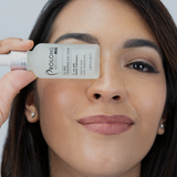 Woman holding Prolong Lash under eye serum bottle near her eye