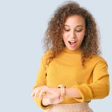 Women in a yellow shirt looking at a wrist watch looking surprised | Prolong Lash