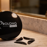  Prolong x Flutterstop black compact case displayed on a marble bathroom countertop with reusable black under eye pads placed in front